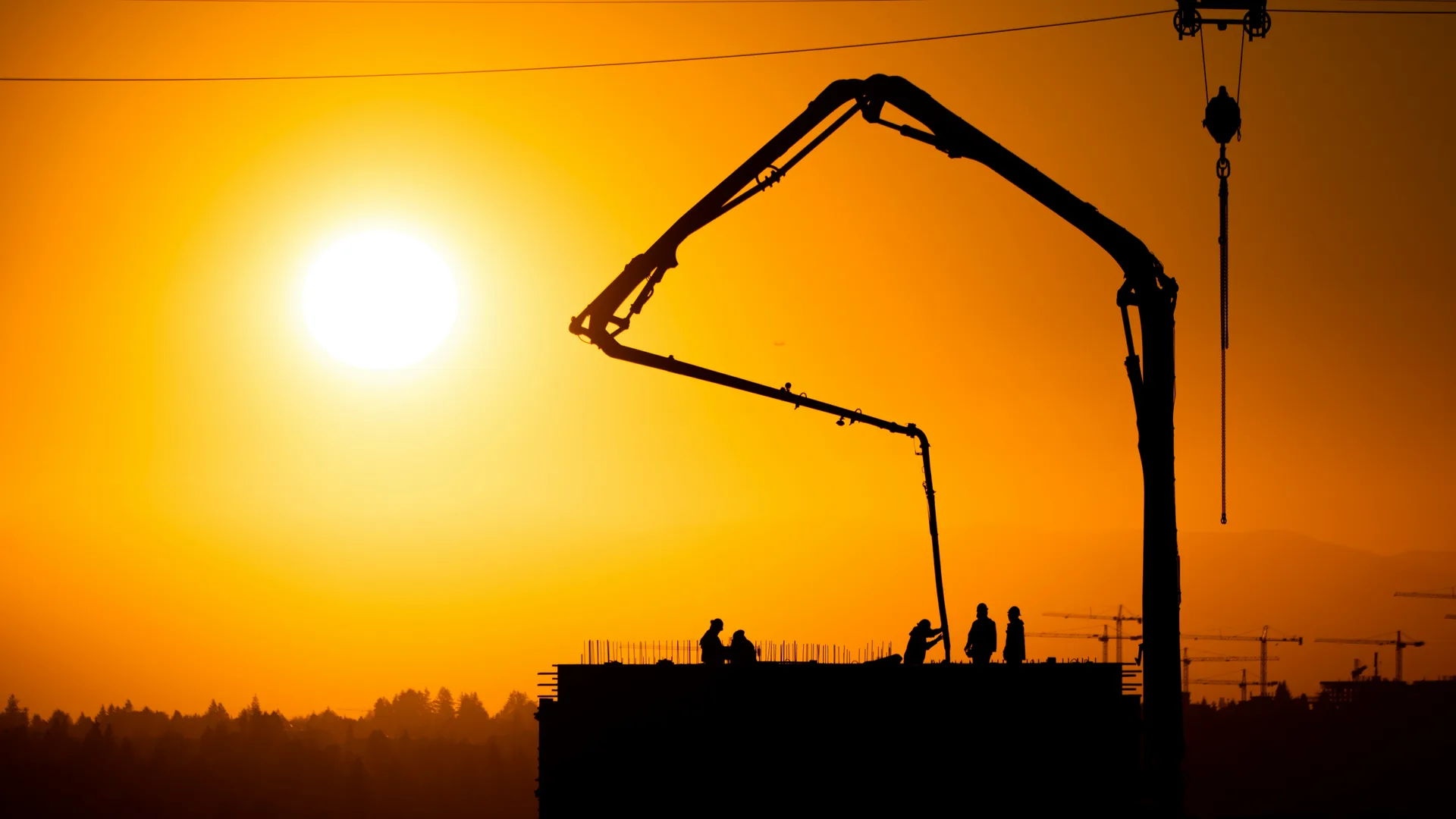 concrete boom pump on a Laval construction site at sunset
